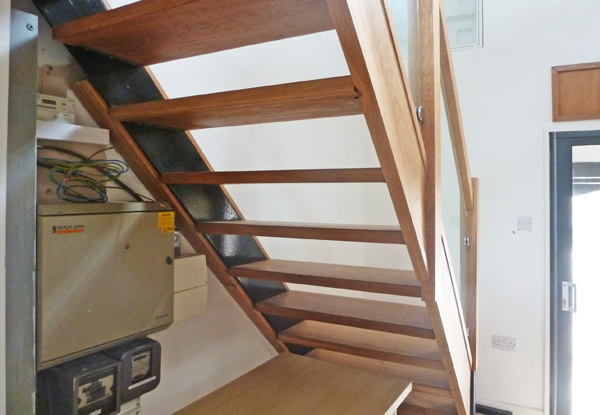 Area under stairs with electrical installation and bundles of cables from heater panels before work had been carried out.