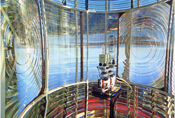 The inside of a lighthouse showing the lamp surrounded by the Fresnel lens that rotates around it and concentrates the light into a beam.